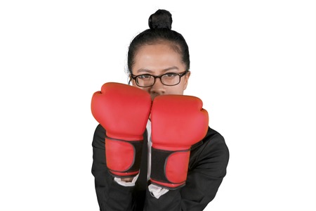 Picture of young businesswoman wearing boxing gloves with defend poses, isolated on white backgroundの写真素材