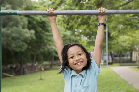 Picture of little girl looks happy while playing with a horizontal bar. Shot in the meadowの写真素材