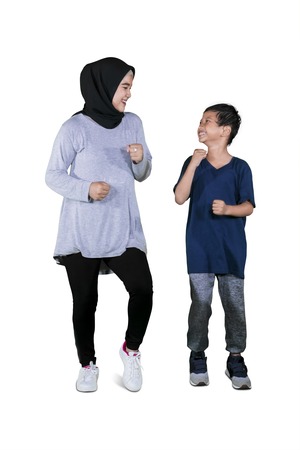 Full length of young woman wearing islamic clothes while jogging with her son in the studioの写真素材