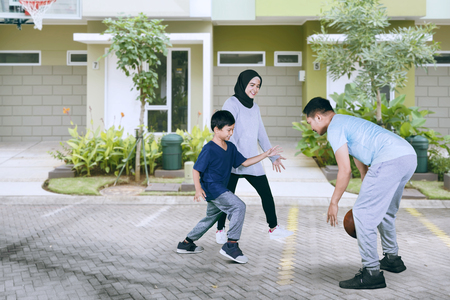 Picture of a little boy playing basketball with his parents in the drivewayの写真素材