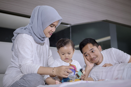 Picture of young parents playing with their baby girl in the bedroomの写真素材