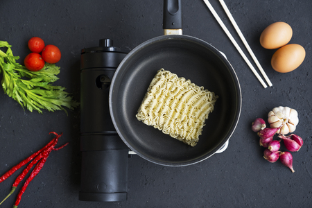 Top view of instant noodle on the saucepan with seasoning ingredients over tableの写真素材