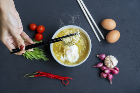 Close up of unknown woman hands holding boiled noodle with chopstickの写真素材