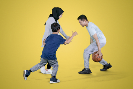 Picture of Muslim family playing basketball in the studio while exercising together with yellow backgroundの写真素材