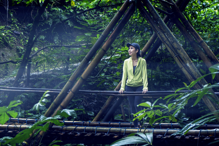Picture of young woman enjoying scenery of Situ Gunung while standing on the suspension bridgeの写真素材