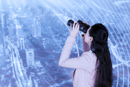 Back view of female entrepreneur using binoculars for looking at an opportunityの写真素材