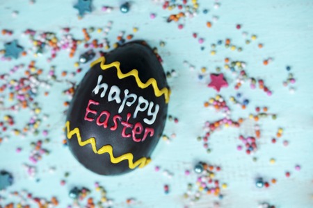 Top view of chocolate egg written with happy Easter text on wooden the table