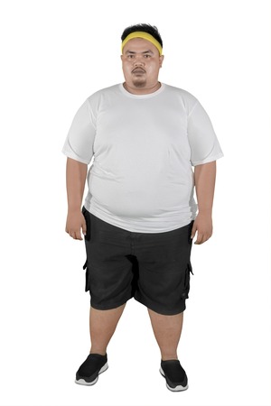 Full length of a young fat man wearing sportswear while standing in the studio, isolated on white background