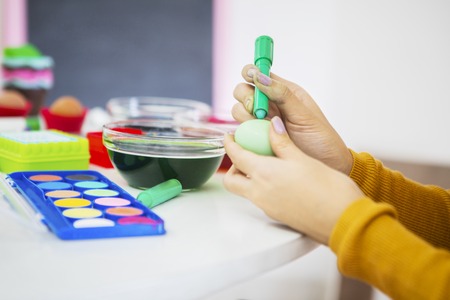 Close up of unknown woman hands painted eggs while doing preparation for Easter at home