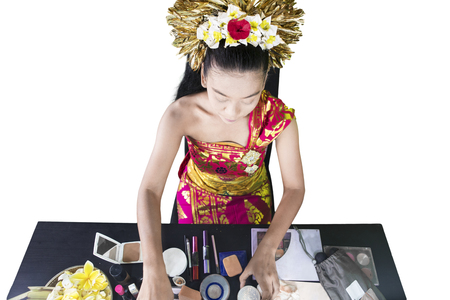 Top view of a female traditional dancer doing makeup before performing, isolated on white backgroundの写真素材