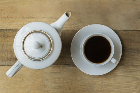 Top view of a cup of black coffee and a coffee pot on the wooden tableの写真素材