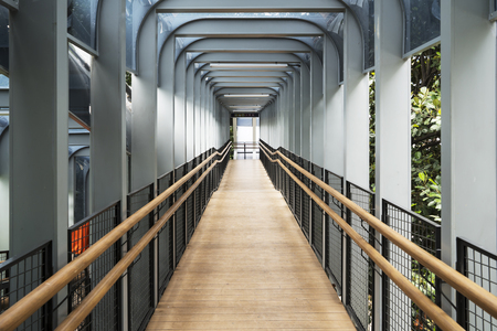 Beautiful interior of modern pedestrian bridge with wooden floor above Sudirman highway.