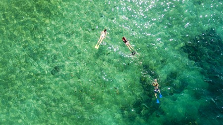 Aerial view of little children snorkeling with their mother in the turquoise water. Shot in Lombok,...