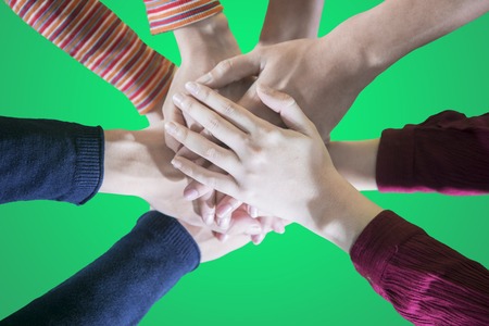 Top view hands of young people support each other by joining their hands together in green screen backgroundの写真素材