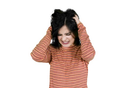 Stressed woman scratching her head and standing in the studio, isolated on white background