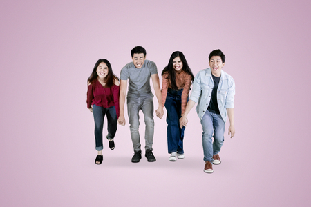Group of young people looks happy while holding hands and walking together  in the studioの写真素材