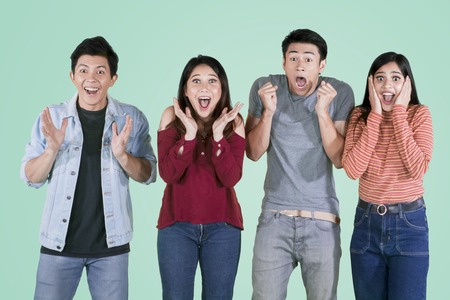 Group of young people standing together with surprised expression in the studio