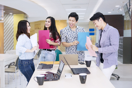 Group of business team looks happy while holding paperwork after working in the officeの写真素材