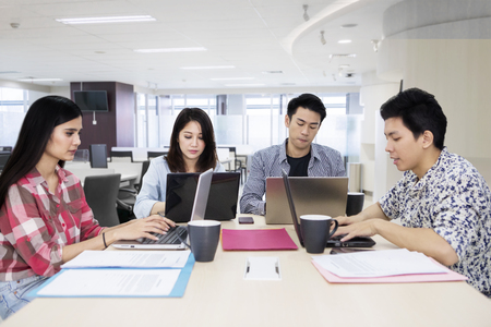 Group of young freelancers using laptop while working together in the officeの写真素材
