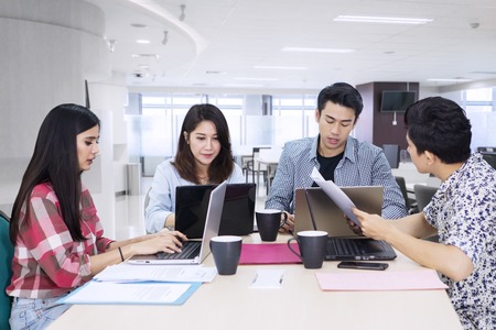 Group of young business people using computer laptops while working together in the officeの写真素材