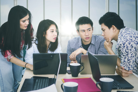 Picture of four business people discussing business strategy while working together near the windowの写真素材