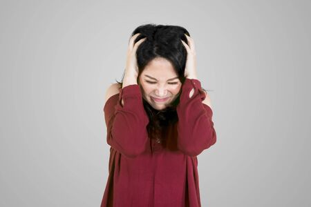 Picture of a stressed woman touching her head and standing in the studioの写真素材