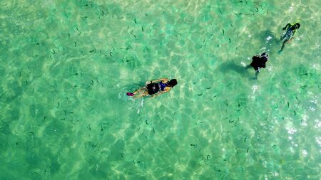 Aerial view of three people snorkeling together in the turquoise water. Shot in Lombok, Indonesiaの写真素材