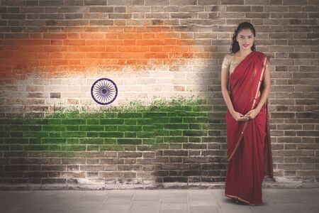 Picture of beautiful woman wearing red saree clothes while standing with India flag backgroundの写真素材