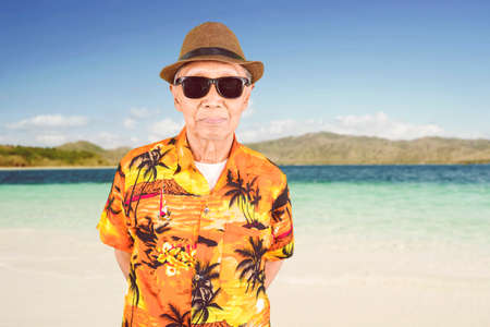 Close up of senior man wearing sunglasses and summer clothes on the beachの写真素材