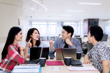 Portrait of happy business team discussing new project in the meeting while sitting in the officeの写真素材