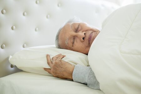 Close up of senior man sleeping well on the comfortable bed with a blanket. Shot at home