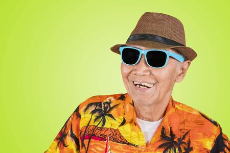 Close up of happy old man wearing sunglasses and summer clothes in the studio