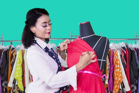 Picture of young woman adjusting a dress on a mannequin while working in the workplaceの写真素材