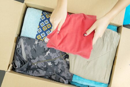 High angle of unknown woman putting clothes in a cardboard boxの写真素材