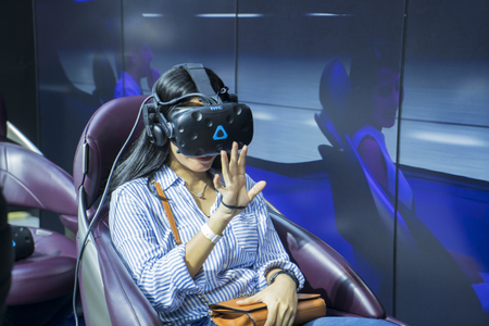 Tangerang - Indonesia. July 24, 2019: Female visitor wearing a VR glasses and trying a driving simulator at event of Gaikindo Indonesia International Auto Show (GIIAS) 2019のeditorial素材