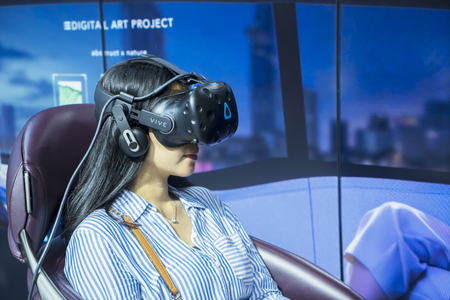 Tangerang - Indonesia. July 24, 2019: Young woman wearing a VR glasses and testing a driving simulator at event of Gaikindo Indonesia International Auto Show (GIIAS) 2019のeditorial素材