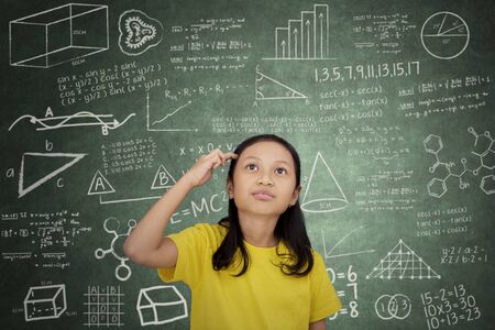 Picture of female elementary school student thinking an idea while standing in the classroom