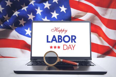 Image of magnifier and Happy Labor Day text on a screen laptop with American flag backgroundの写真素材