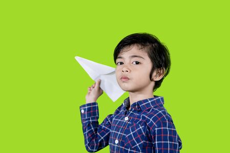 Picture of Asian little boy playing a paper plane while playing in the studio with green screenの写真素材