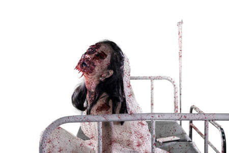 Portrait of scary bride ghost screaming and sitting on the hospital bed, isolated on white...