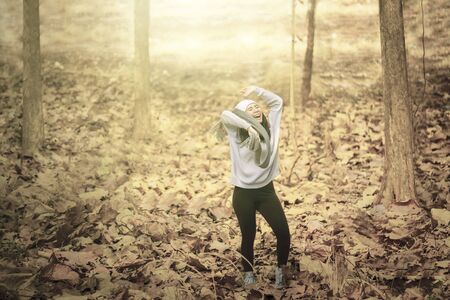 Picture of Asian young woman looks happy while dancing in the autumn park with dried autumn foliageの写真素材