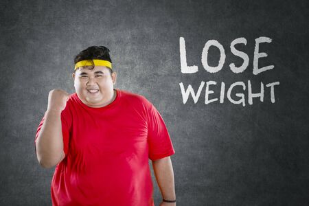 Young fat man wearing sportswear while expressing happy with text of Lose Weight on backgroundの写真素材