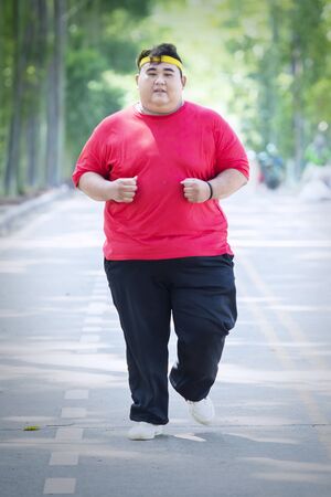 Portrait of an Asian fat man wearing sportswear while doing run exercises in the parkの写真素材