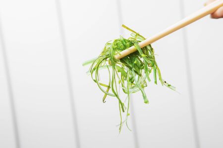 Close up of wakame seaweed salad with chopsticks. Healthy food conceptの写真素材