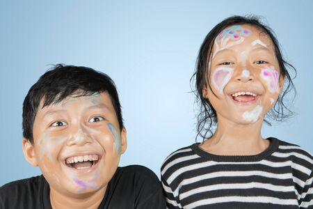 Picture of two little children smiling at the camera with face painting in the studio
