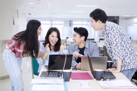 Group of young business people looks happy while working with laptops in the officeの写真素材