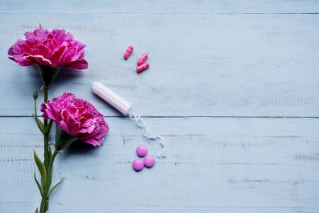 Top view of two roses and pills with tampon on the wooden table