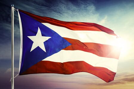 Puerto Rico flag fluttering on a flagpole with sunrise background at dawning timeの写真素材