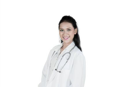 Caucasian female doctor smiling at the camera while standing in the studio, isolated on white backgroundの写真素材