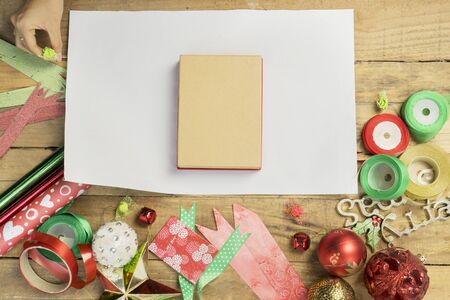 High angle view of unknown woman hands prepare to pack a Christmas gift with ornaments on the wooden tableの写真素材